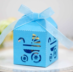 Detail of blue laser-cut candy box featuring a baby carriage pattern with a silk ribbon
