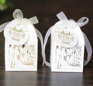 Close-up of white laser-cut Mr & Mrs wedding favor box with thank you tag and ribbon