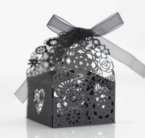 Détail de la boîte cadeau noire découpée au laser avec motifs floraux et ruban en mousseline