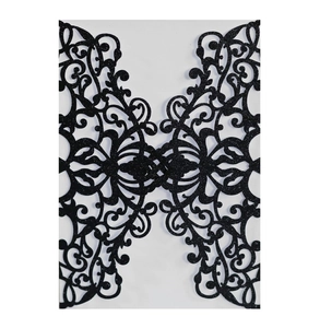 Close-up of laser-cut black glitter invitation cover with elegant floral patterns