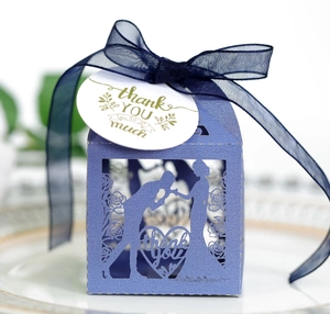 Detail of laser-cut navy blue wedding favor box with thank you tag and ribbon bow