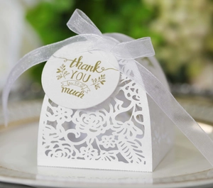 Macro detail of white laser-cut rose wedding gift box with ribbon and thank you tag