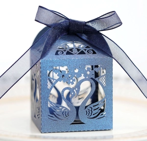 Detail of laser-cut hollow swan wedding favor box in navy blue with organza ribbon bow