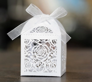 Macro shot of laser-cut white rose gift box with elegant organza bow on dark wood