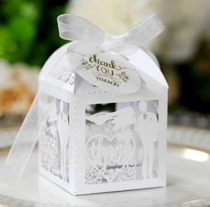 Detail of laser cut wedding favor box with heart patterns and white ribbon bow