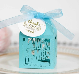 Detail of laser-cut Mr & Mrs wedding candy box with blue ribbon and thank you tag