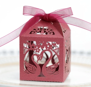 Macro detail of wine red laser-cut candy box with elegant swan heart pattern and ribbon