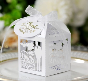 Detail of white laser-cut wedding favor box with ribbon and gold foil thank you tag