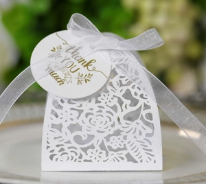 Macro view of white laser-cut wedding gift box with rose patterns and ribbon