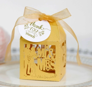 Close-up of laser-cut hollow gold wedding favor box with ribbon and thank you tag
