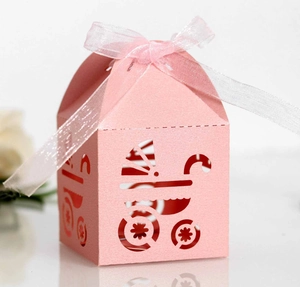 Close-up of pink laser-cut candy box with baby stroller pattern and white ribbon