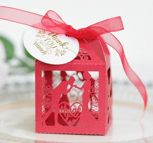Detail view of red laser-cut wedding favor box with rose patterns and thank you tag