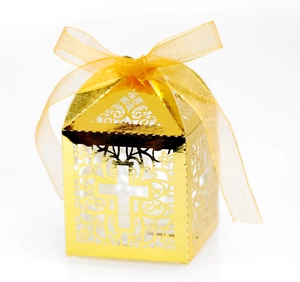 Detail of laser-cut gold cross favor box with decorative yellow satin ribbon bow