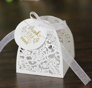 Macro detail of white laser-cut wedding gift box with rose pattern and thank you tag