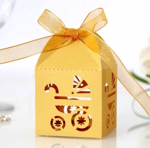 Macro detail of yellow laser-cut gift box with stroller design and chiffon ribbon