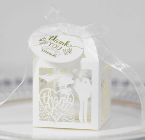 Laser-cut white wedding favor box with ribbon, thank you tag, and couple silhouette