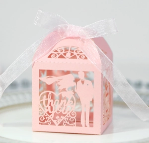 Détail de la boîte à bonbons de mariage rose découpée au laser avec silhouette de mariés