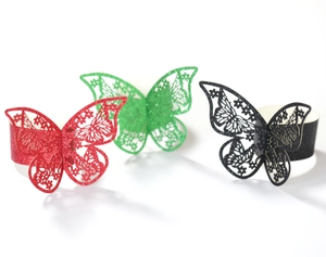 Detalle de servilleteros de mariposa con purpurina cortados con láser en rojo, verde y negro