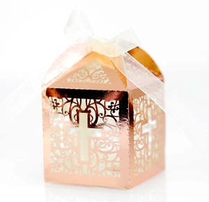 Close-up of laser-cut cross design on rose gold gift box with white silk ribbon