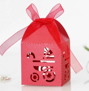 Detail of red laser-cut candy box with stroller patterns and matching organza ribbon bow