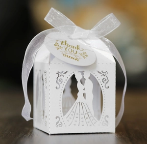Detail of laser-cut wedding favor box with ribbon and golden thank you tag