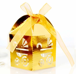 Detail of laser-cut baby carriage pattern on golden candy box with organza ribbon bow