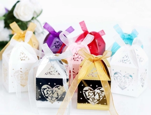 Close-up of colorful heart-shaped LOVE cut-out wedding favor boxes with satin ribbons