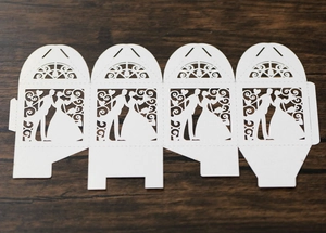 Detailed laser-cut template of a white wedding favor box with bride and groom silhouette