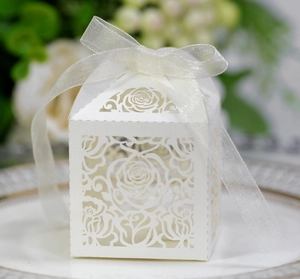 Detail of white laser-cut rose gift box with elegant organza ribbon on ceramic tray
