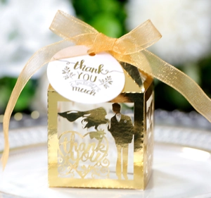 Detail of gold hollow wedding candy box with laser-cut silhouettes and thank you tag