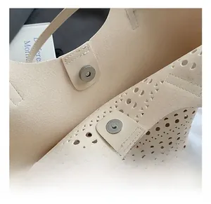 Détail du motif ajouré au laser et du fermoir magnétique argenté sur le sac beige