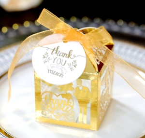Detail of laser-cut gold wedding favor box with bride silhouette and thank you tag