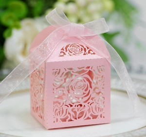 Pink laser-cut gift box with intricate floral hollow design and white organza ribbon bow