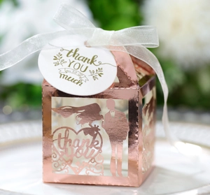 Close-up of rose gold laser-cut wedding favor box with ribbon and thank you tag