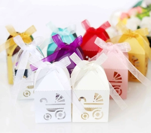 Detail of laser-cut baby carriage candy boxes in multiple colors with ribbon bows