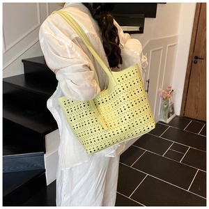 Détail du sac cabas jaune découpé au laser avec motif évidé porté à l'épaule par un mannequin