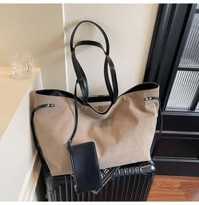 Detail of khaki tote bag with black leather straps and hanging pouch on suitcase