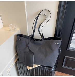 Detail of charcoal canvas tote bag with removable coin purse on a suitcase