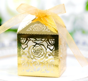 Detail of laser-cut rose patterns on a gold gift box with a sheer organza ribbon bow