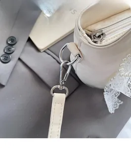 Détails macro des ferrures argentées et dentelle de perles sur un sac crème chic