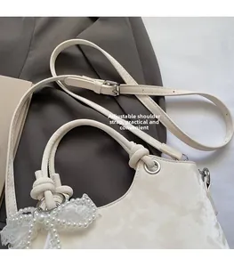 Détail du sac seau blanc avec nœud en dentelle, pendentif perle et sangle réglable