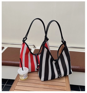 Detail of red and black striped mesh tote bags with leather straps on a wooden bench