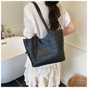 Détail du motif géométrique ajouré au laser sur un sac cabas noir en cuir synthétique