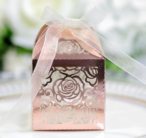 Macro detail of laser-cut rose gold candy box with elegant white organza ribbon bow