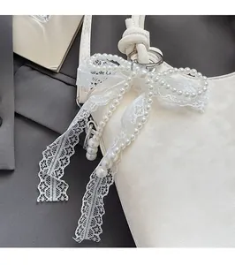 Détail d'un élégant bijou de sac avec perles blanches, nœud papillon et ruban en dentelle