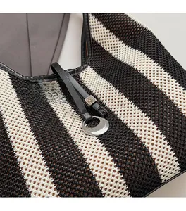 Detail showing woven mesh texture and luxury metal charm on striped tote bag