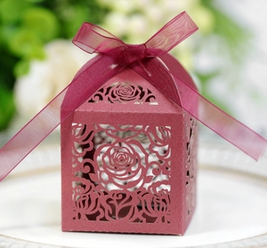 Macro shot of dark red laser-cut rose gift box with a matching ribbon on a white plate