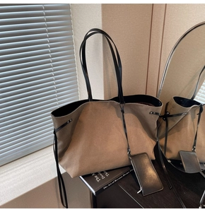 Detail view of large brown suede tote bag with black straps and small coin purse attachment