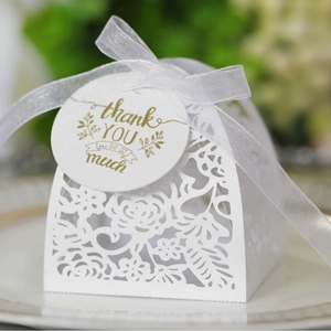 Elegant white laser-cut floral wedding favor box with silk ribbon and golden thank you tag