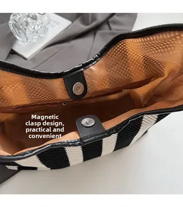Detail of magnetic buckle closure and internal zipper pocket in woven tote bag